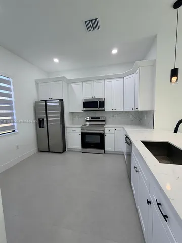 a kitchen with refrigerator a microwave and cabinets