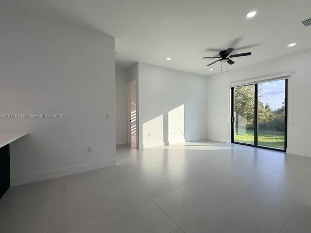 a view of an empty room with a window and kitchen