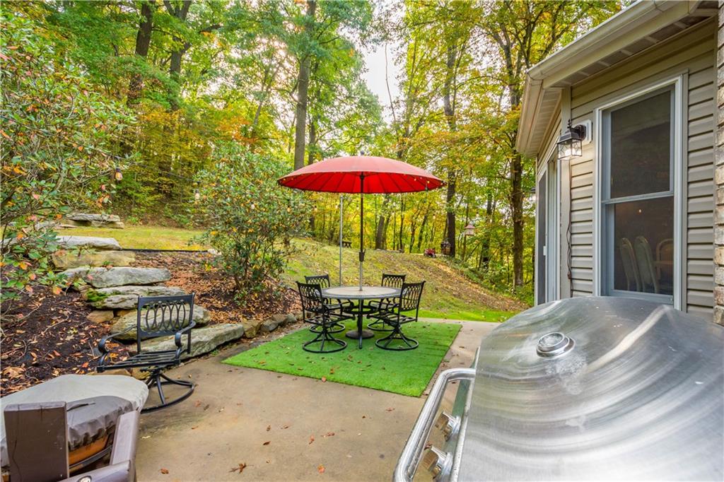 314 Glade Run Road Renfrew, PA 16053 - Photo 20 of 24 a view of a patio with table and chairs under an umbrella with a fire pit