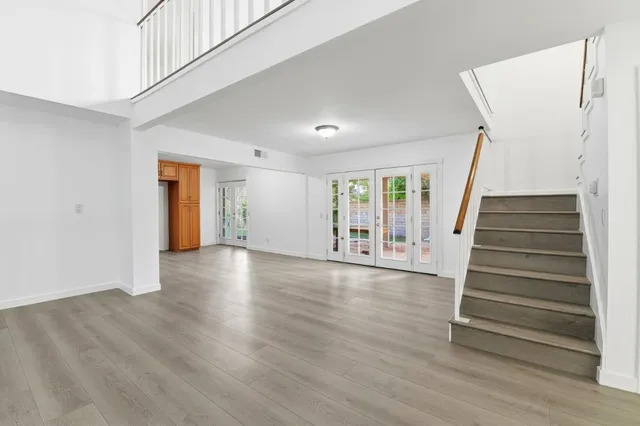 a view of an empty room with wooden floor and stairs
