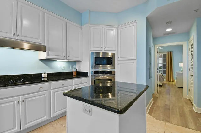 a kitchen with granite countertop a sink stainless steel appliances and white cabinets