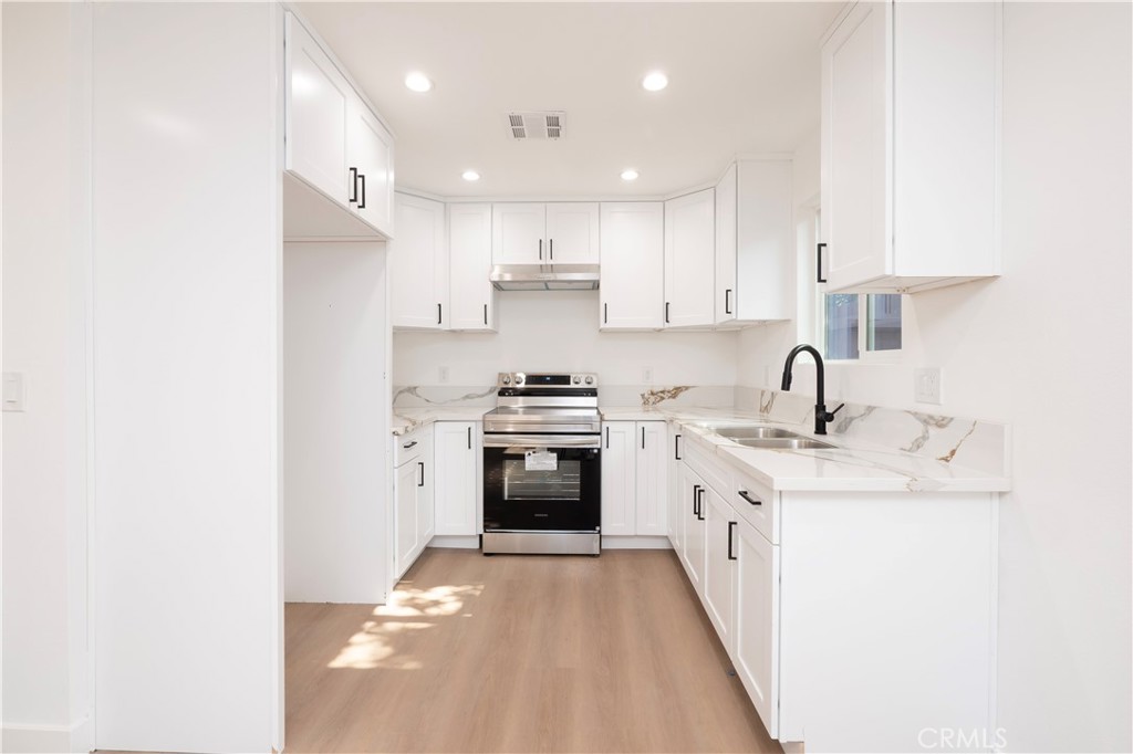 5741 South St Andrews Place, Unit 1/2 Los Angeles, CA 90062 - Photo 16 of 28 a kitchen with stainless steel appliances granite countertop a sink stove oven and white refrigerator