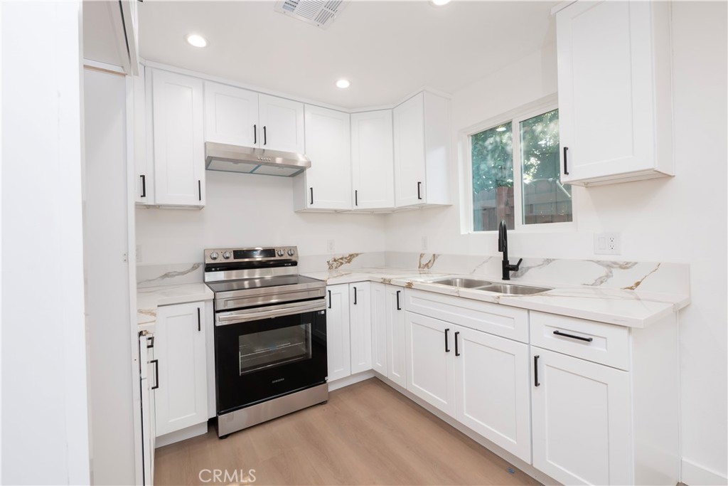 5741 South St Andrews Place, Unit 1/2 Los Angeles, CA 90062 - Photo 18 of 28 a kitchen with stainless steel appliances granite countertop a sink and cabinets with wooden floor