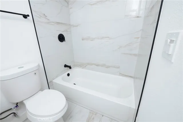 a white toilet sitting next to a tub