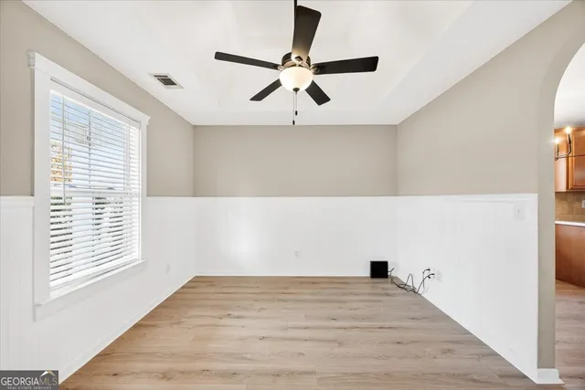 a view of empty room with wooden floor and fan