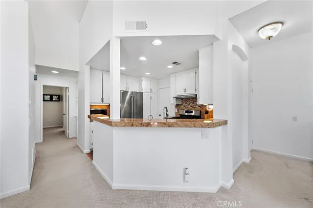 a large white kitchen with stainless steel appliances a refrigerator a stove a microwave and cabinets