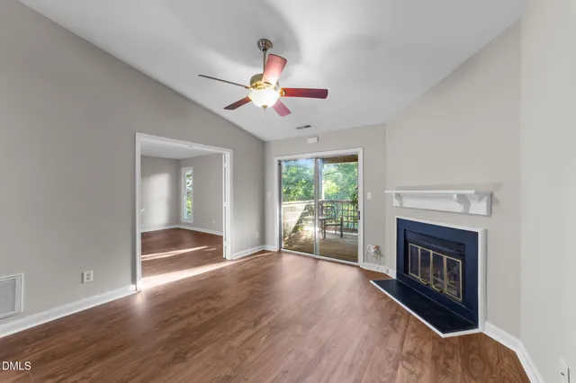an empty room with wooden floor chandelier fan and windows