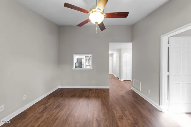a view of an empty room with wooden floor and a fireplace