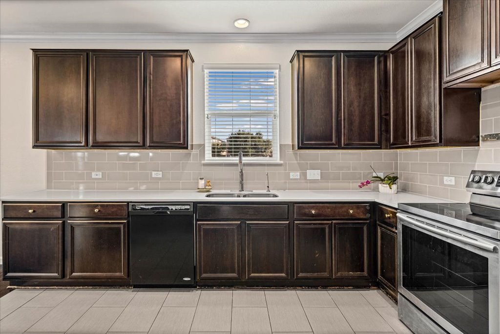 Kitchen featuring stainless steel electric stove, dishwasher, decorative backsplash, and ornamental molding
