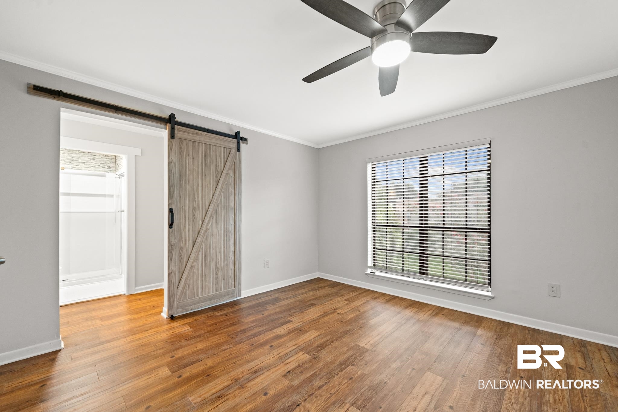 2901 Grant Street, Unit 802 Mobile, AL 36606 - Photo 18 of 37 Unfurnished room featuring hardwood / wood-style flooring, ornamental molding, a barn door, and ceiling fan
