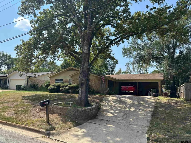 a front view of a house with garden and trees