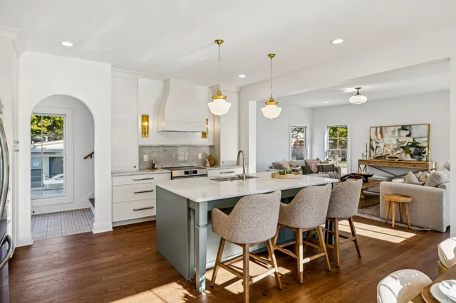 a kitchen with stainless steel appliances a dining table chairs stove and wooden floor