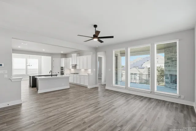 a view of an empty room with kitchen appliances and a ceiling fan