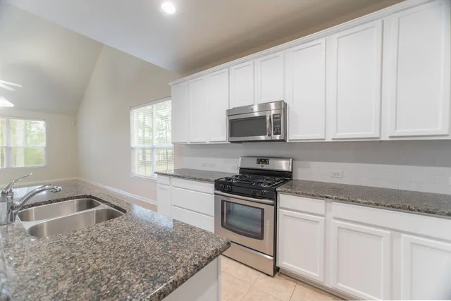 a kitchen with stainless steel appliances granite countertop a sink stove and microwave