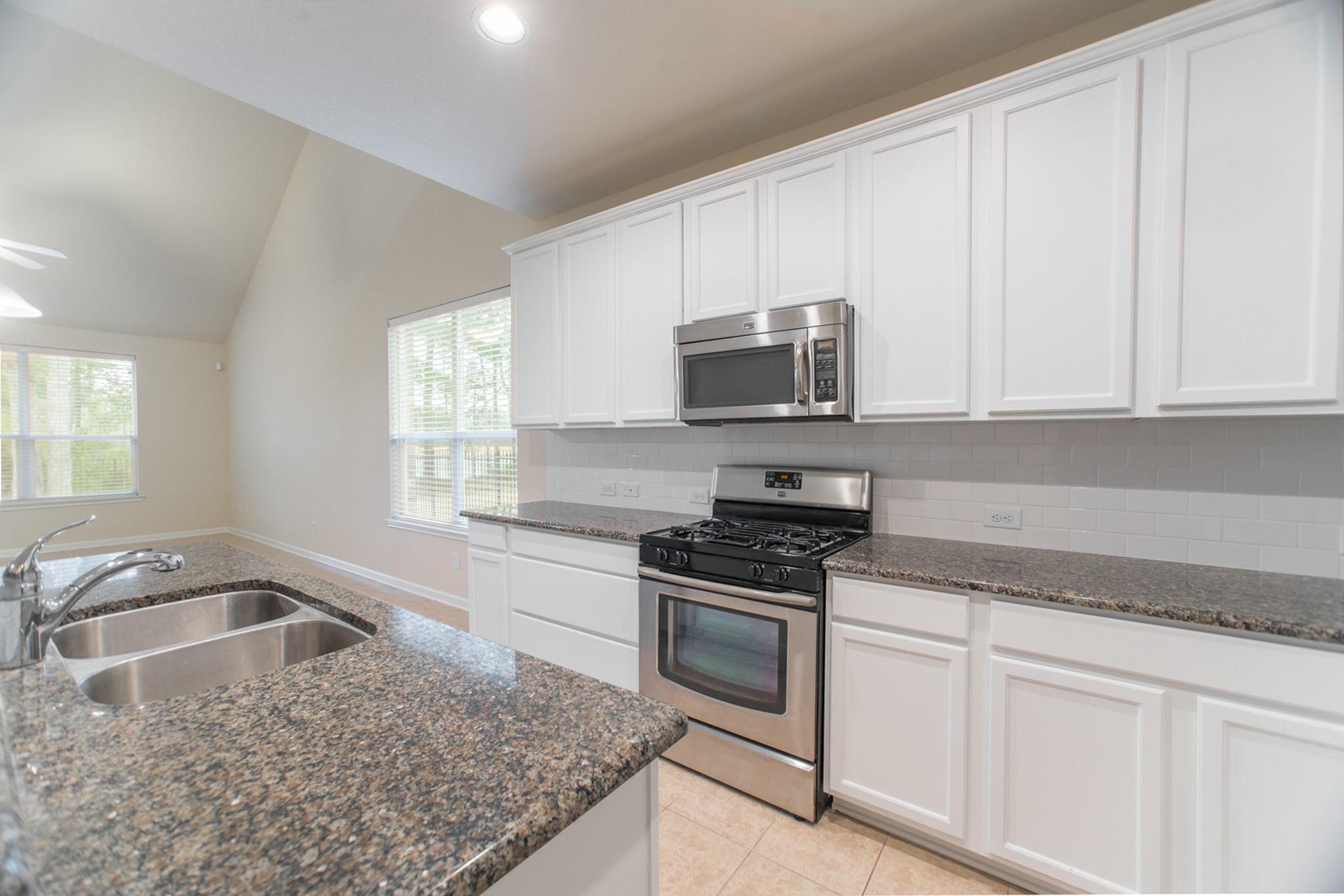 78 East Heritage Mill Circle The Woodlands, TX 77375 - Photo 11 of 50 a kitchen with granite countertop a sink a stove and microwave