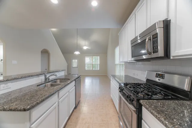 a kitchen with granite countertop a sink and a stove top oven