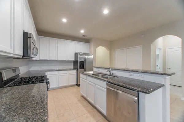 a kitchen with stainless steel appliances granite countertop a refrigerator and a stove