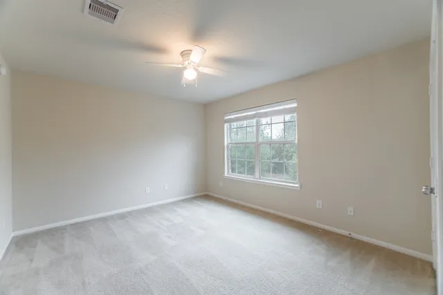an empty room with chandelier fan and windows