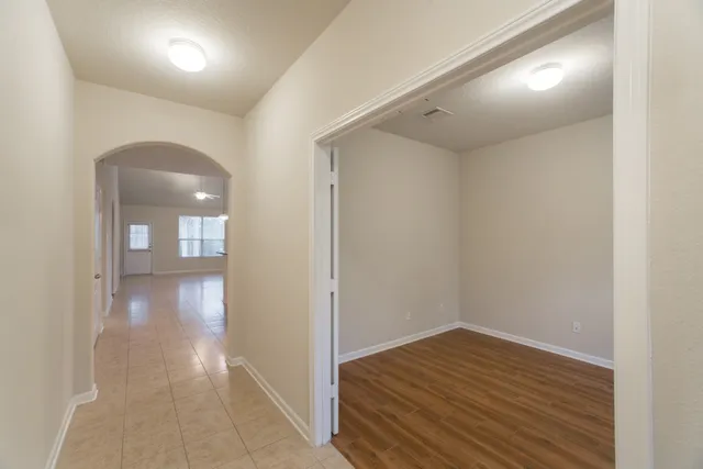 a view of an empty room with wooden floor and a window