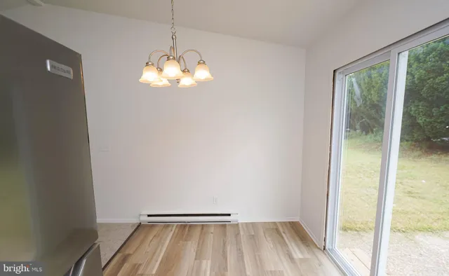 a view of a chandelier in big room with wooden floor and a window