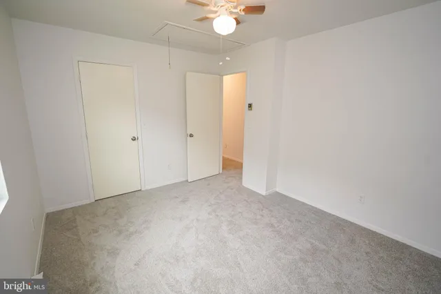 a view of an empty room and chandelier fan