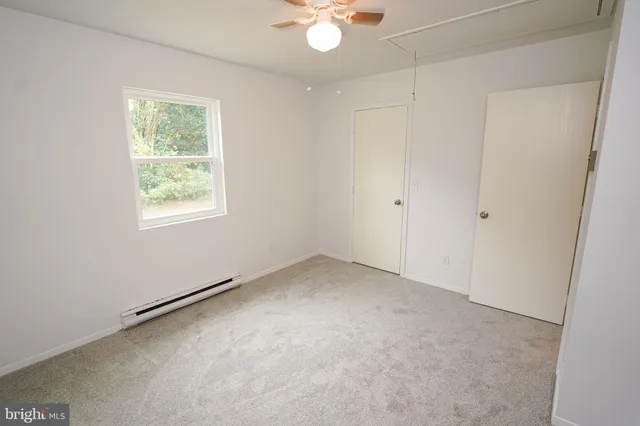 an empty room with a window and a ceiling fan