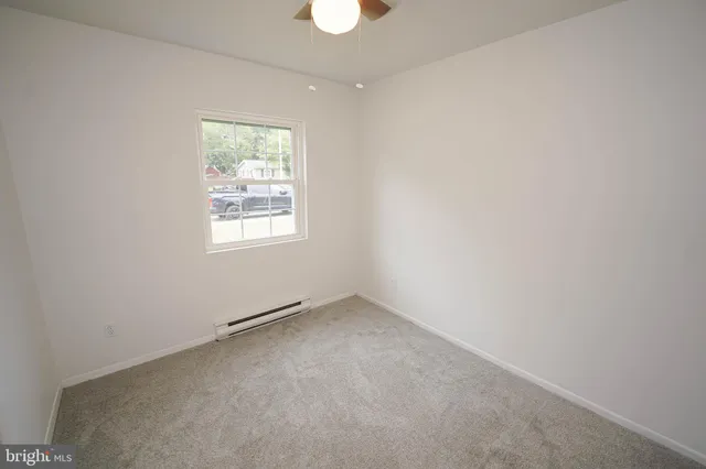 an empty room with chandelier fan and windows