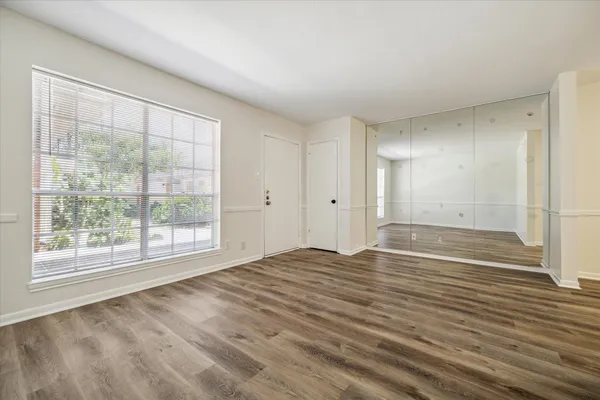 a view of an empty room with wooden floor and a window
