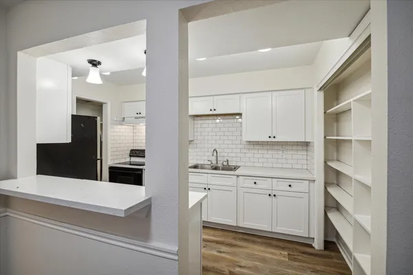 a kitchen with white cabinets and sink