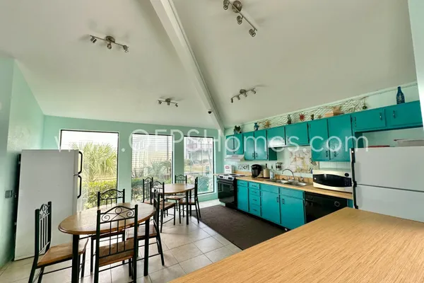 a kitchen with a table chairs refrigerator and cabinets