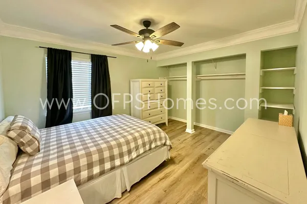 a bedroom with a bed and dresser with wooden floor