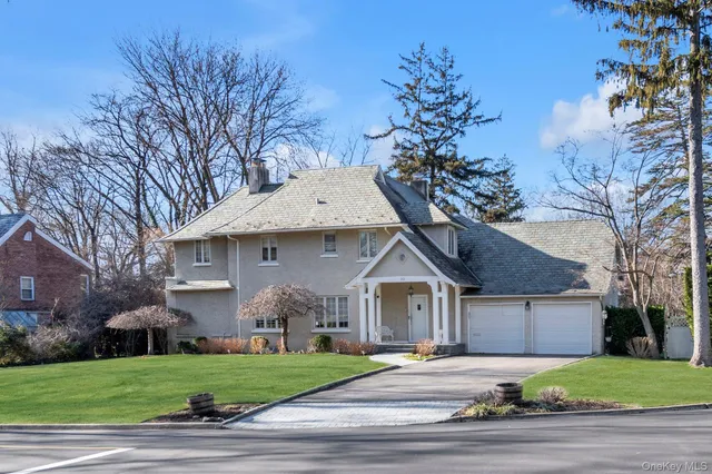 a front view of a house with a garden and trees