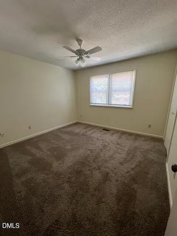 an empty room with a ceiling fan and window