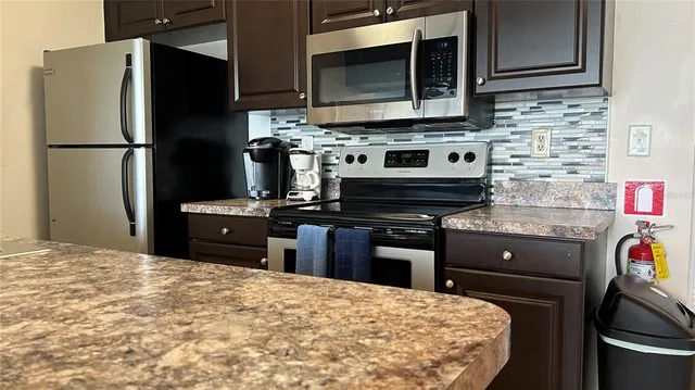 a kitchen with stainless steel appliances kitchen island granite countertop a stove refrigerator and microwave