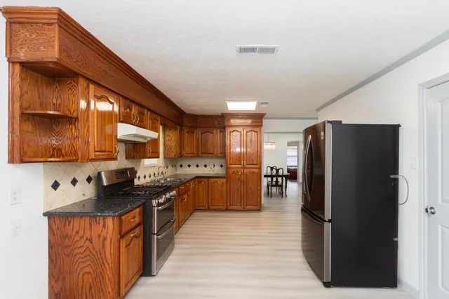 a kitchen with stainless steel appliances granite countertop a refrigerator a sink a stove and a refrigerator