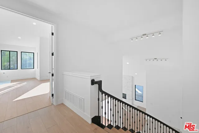 a view of an empty room with wooden floor and window