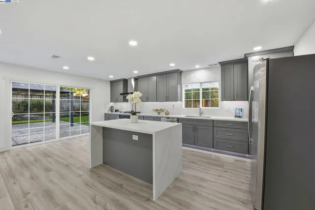 a kitchen with stainless steel appliances granite countertop a sink cabinets and wooden floor