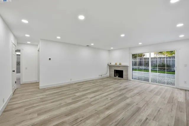 a view of an empty room with wooden floor and a fireplace