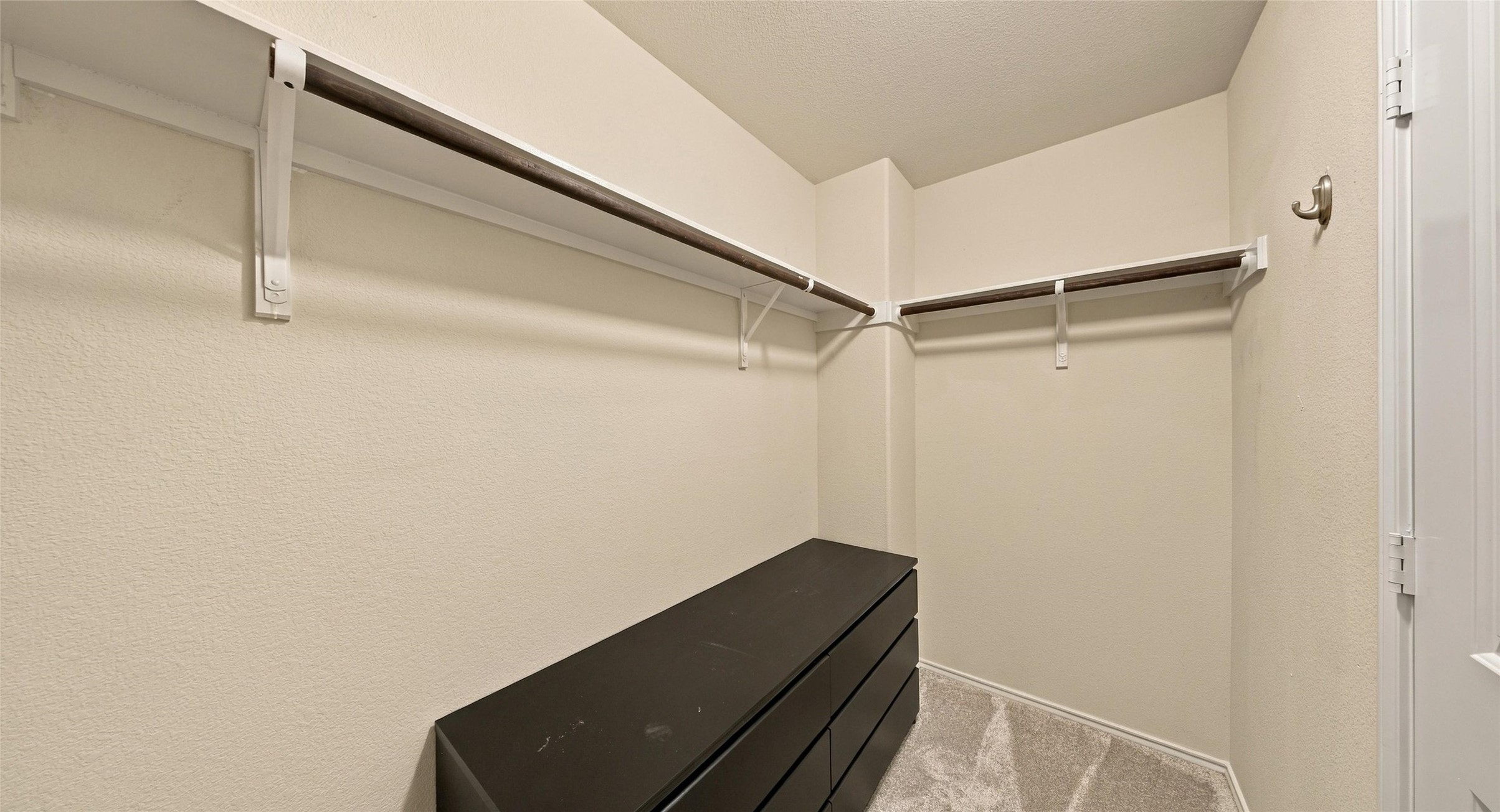 7224 Crestone Road Austin, TX 78744 - Photo 26 of 33 Ample closet space features integrated wooden hanging rods and neutral carpeting.