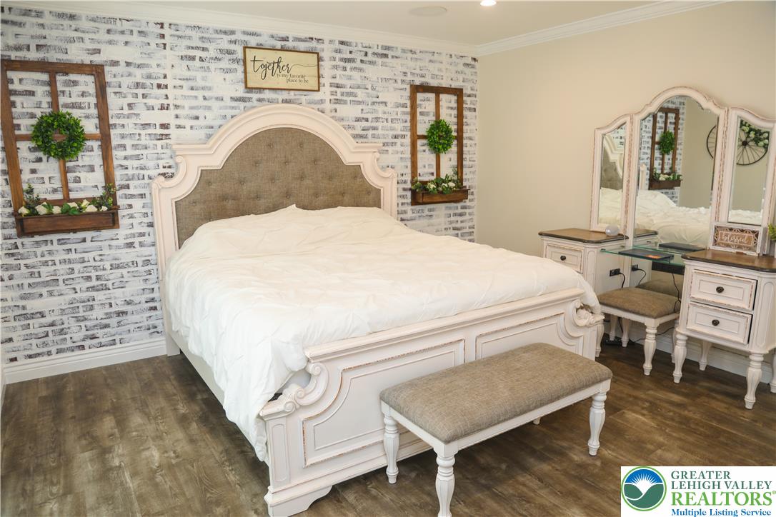 1412 Stanford Road Bethlehem, PA 18018 - Photo 36 of 58 A well-lit primary bedroom features a striking white brick accent wall and durable wood-look flooring.