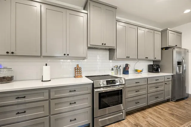 a kitchen with granite countertop white cabinets and stainless steel appliances