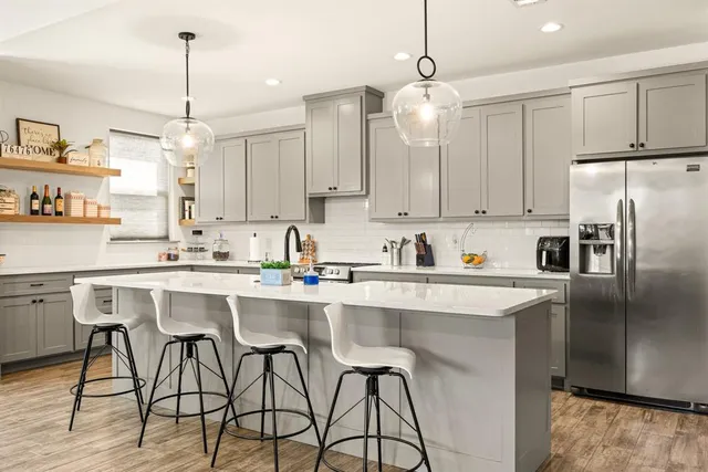 a large white kitchen with a stove a sink dishwasher a dining table and chairs with the living room