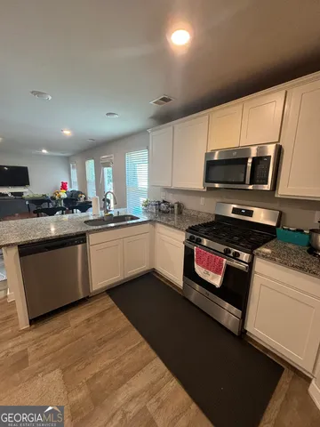 a kitchen with stainless steel appliances granite countertop a stove a sink dishwasher a refrigerator and a microwave