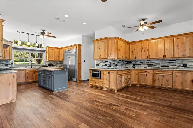 a kitchen with stainless steel appliances kitchen island granite countertop a stove a sink and a refrigerator