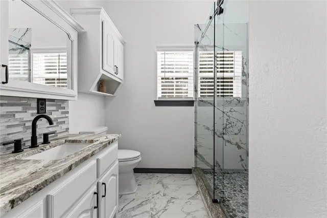 a bathroom with a granite countertop sink toilet a mirror and shower