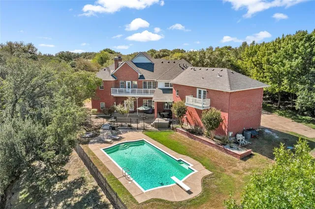 an aerial view of a house with swimming pool and mountains