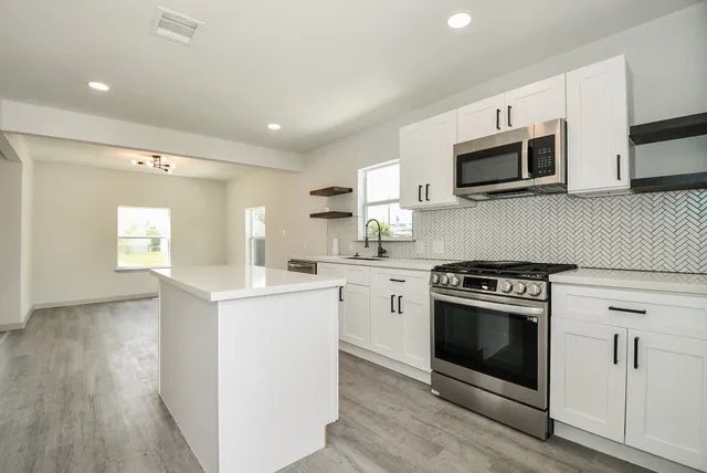 a kitchen with stainless steel appliances white cabinets a sink and a stove