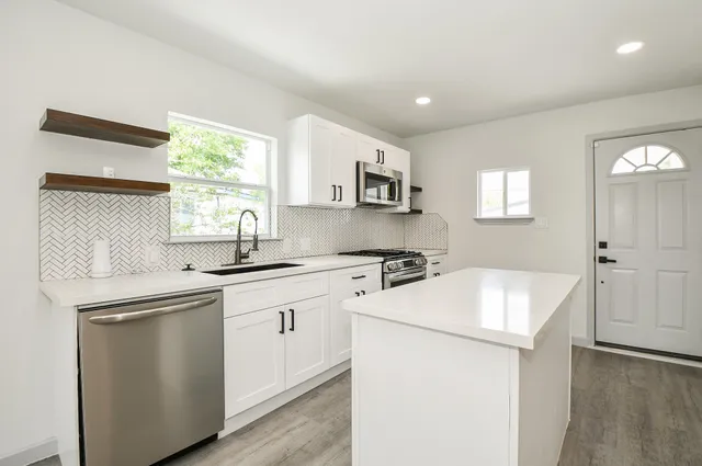 a kitchen with stainless steel appliances white cabinets a sink stove and microwave