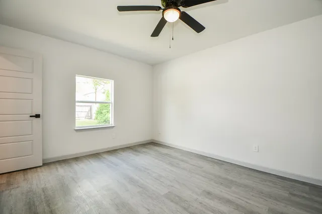 an empty room with a ceiling fan and wooden floor