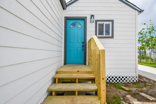 an empty room with wooden floor ceiling fan and windows